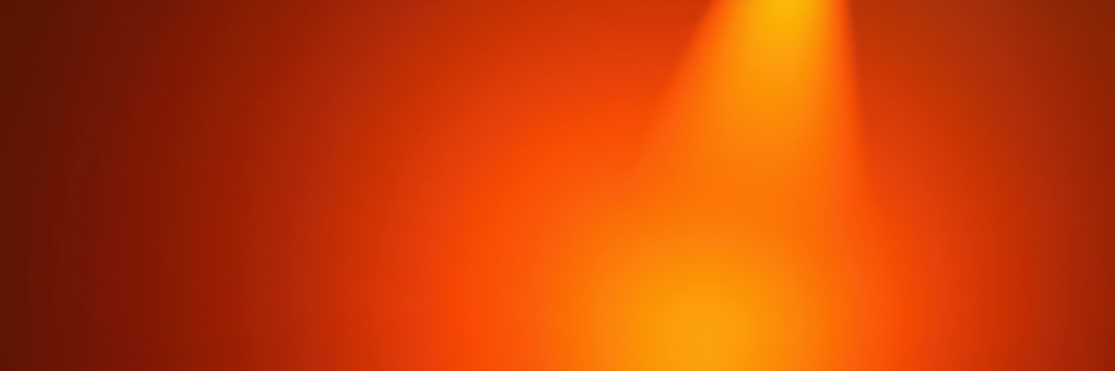 A single spotlight shines brightly on an orange wall